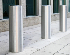 A group of metal poles on a sidewalk protected by PVC corner guards from Warrior WPS.