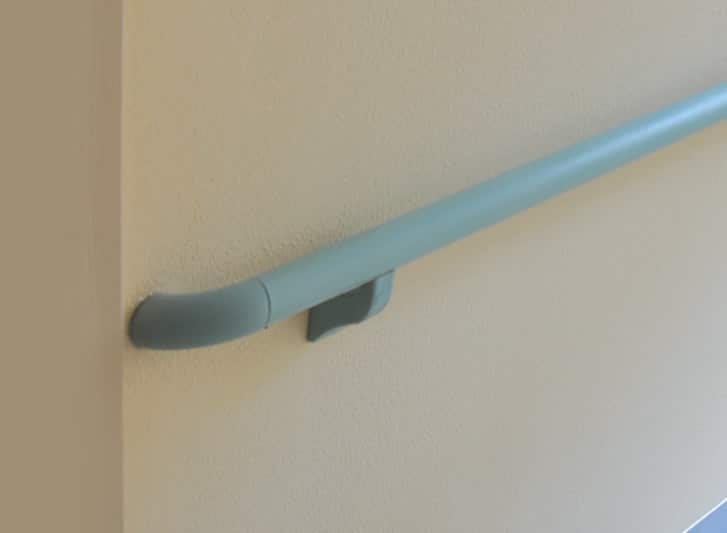 A hallway with a blue handrail attached to the stair wall.