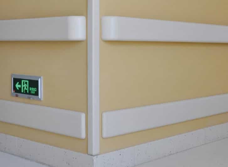 A hospital room with PVC wall guards and white wall panels.