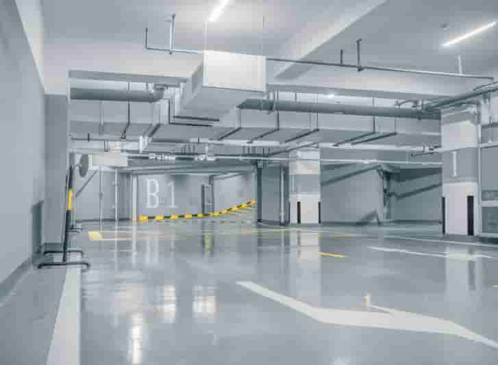 An empty parking garage with yellow lines on the floor and rubber corner guards.