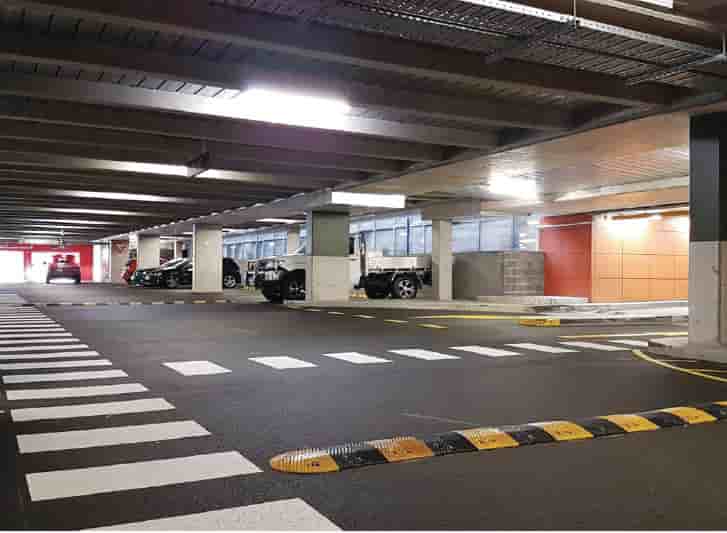 A parking garage with yellow speed humps on a black striped floor.