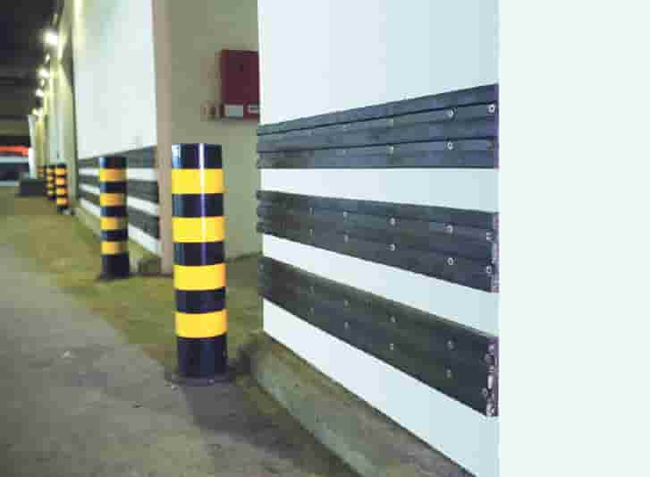 A row of yellow striped poles in a parking garage.