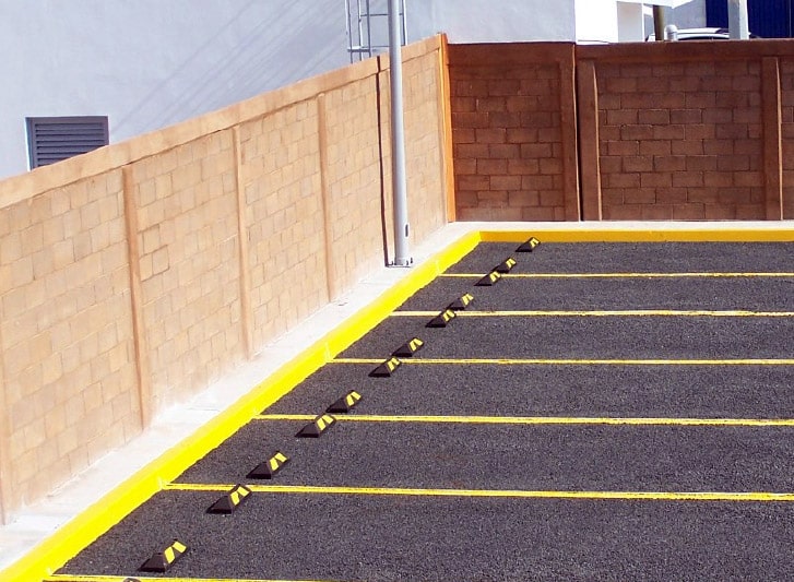 A parking lot with a yellow line and rubber wall guard.