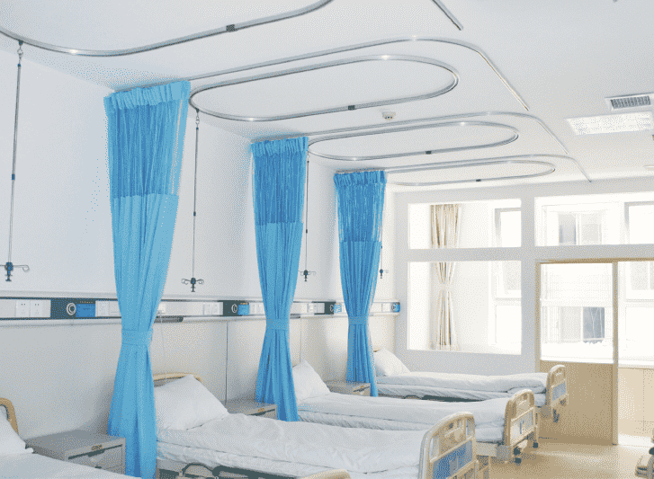Hospital beds in a room with blue curtain rails.