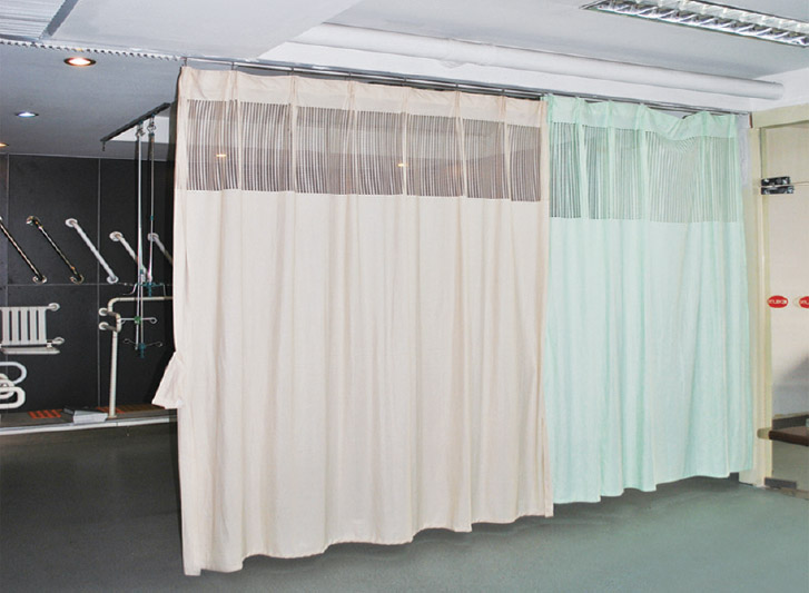 A hospital room with disposable curtains and curtain rails.