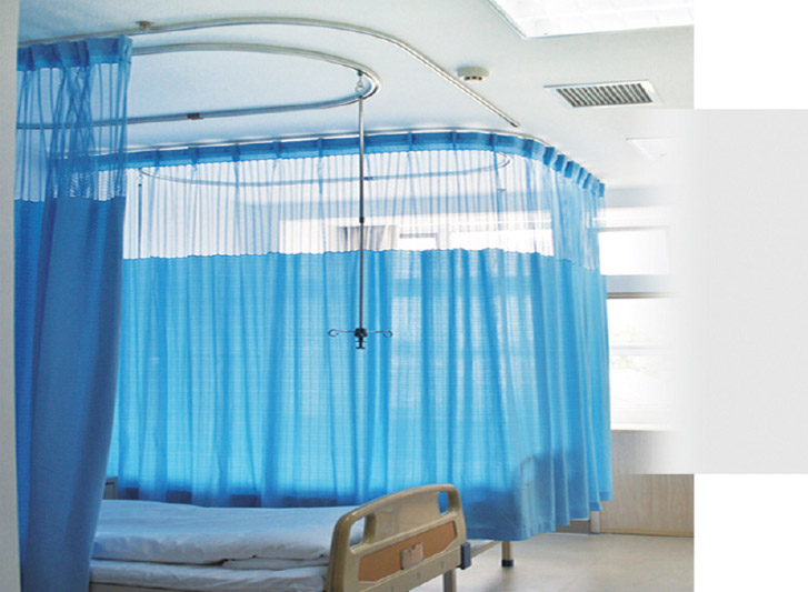 A hospital room with blue curtains and disposable curtain rails.