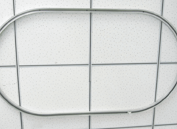 A metal oval shaped curtain rail on a tiled wall.