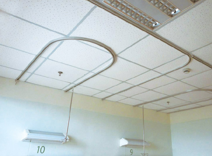A hospital room with a white ceiling and disposable curtains.