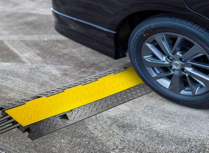 A black car with a yellow ramp attached to it for cable protectors.