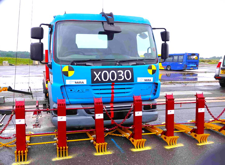 A blue truck parked in a parking lot with stainless steel bollards.