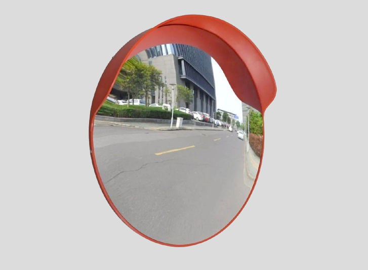 A convex traffic mirror on the side of a road.