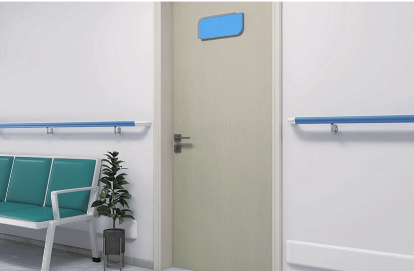 A hospital room with blue chairs, a blue door, and PVC handrails.