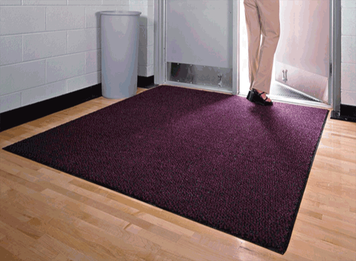 A woman standing in front of a PVC entrance mat.