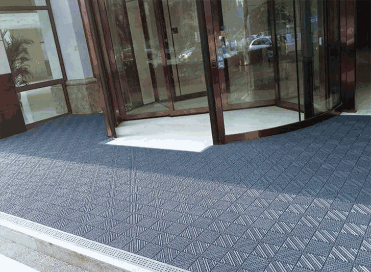 A blue entrance mat with a glass door in front of it, made of aluminium.