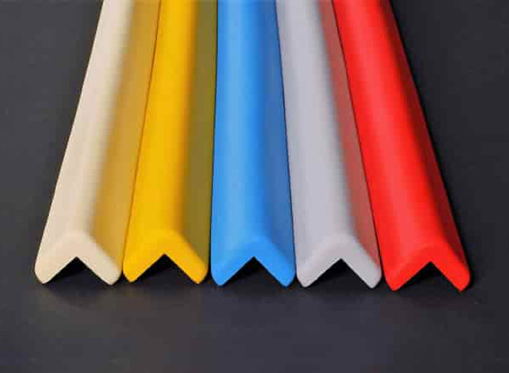 A row of foam corner and wall guards on a black surface, with colored plastic arrows.