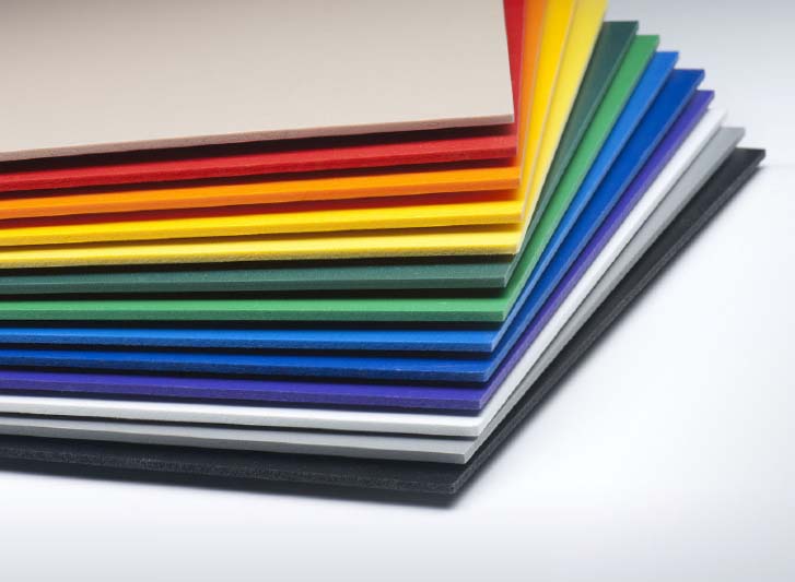 A stack of colored plastic sheets for wall panels on a white surface.