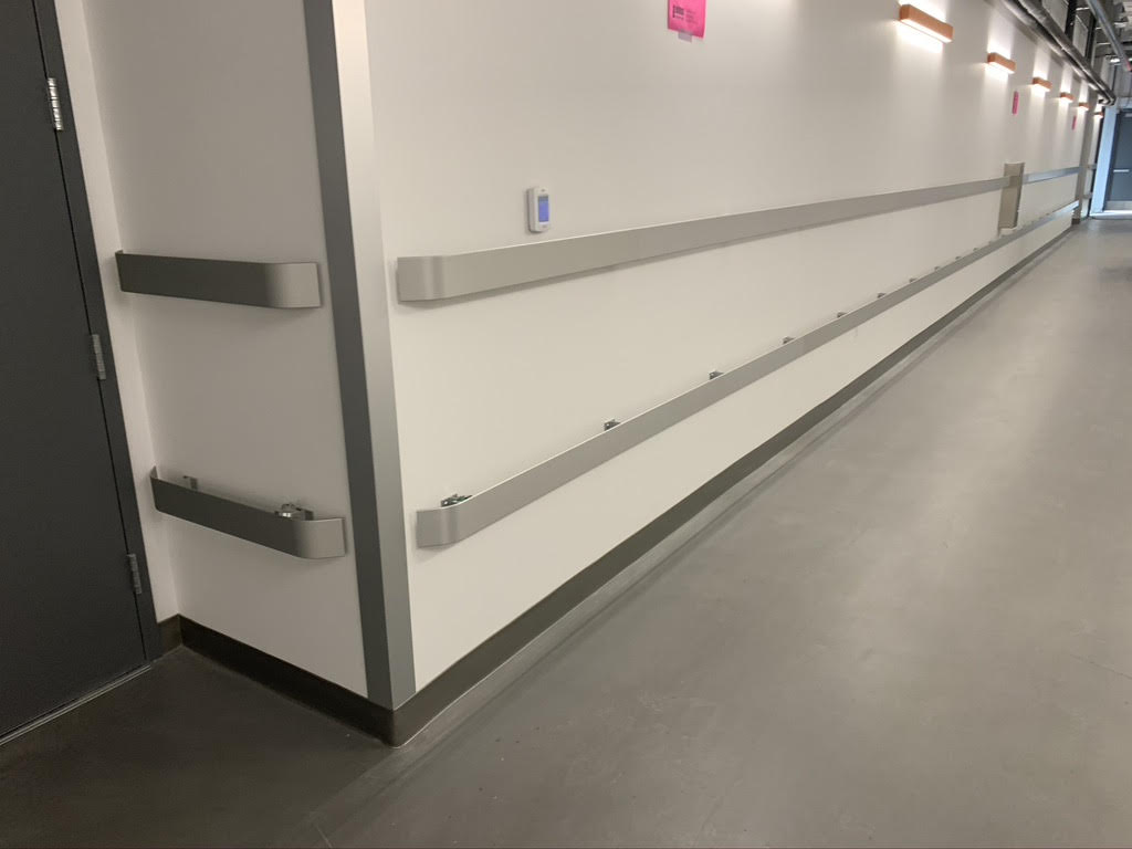 A hospital hallway with stainless steel handrail and metal railings.